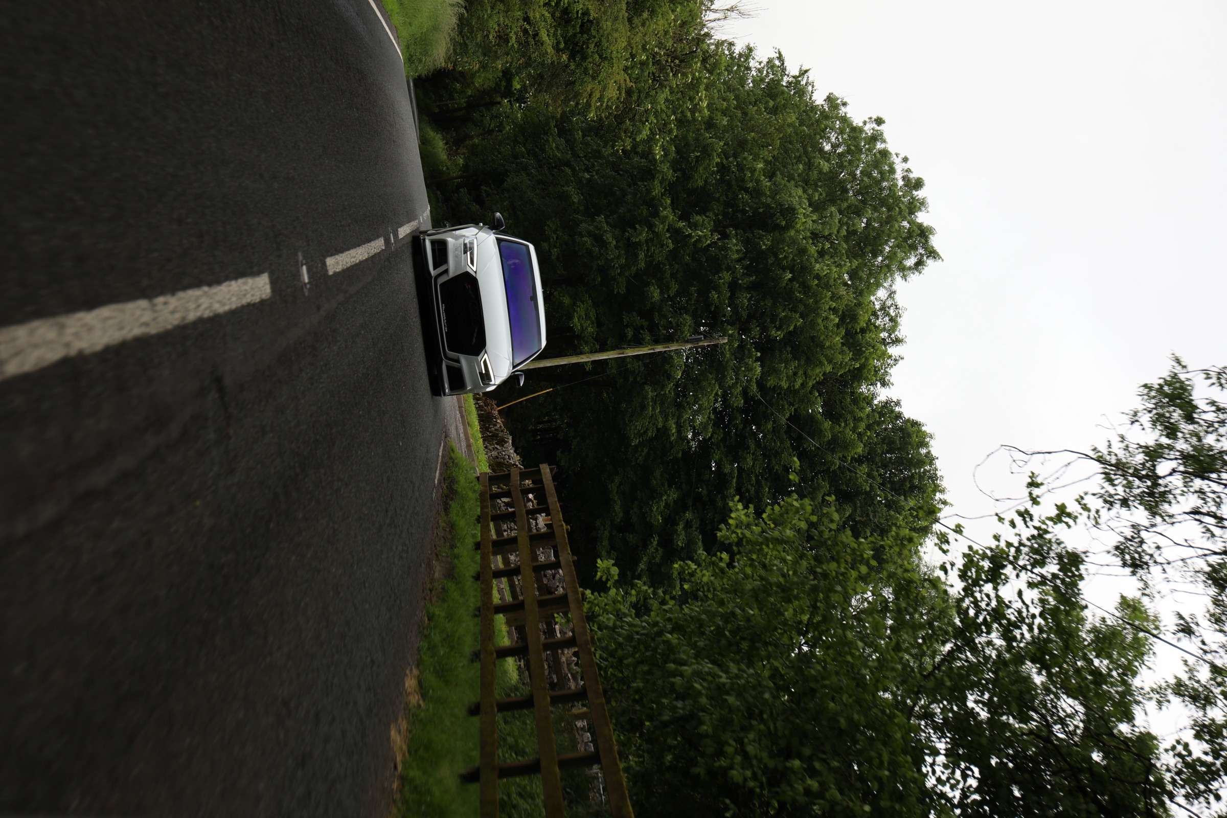 A white Audi on a tree-lined country B-road